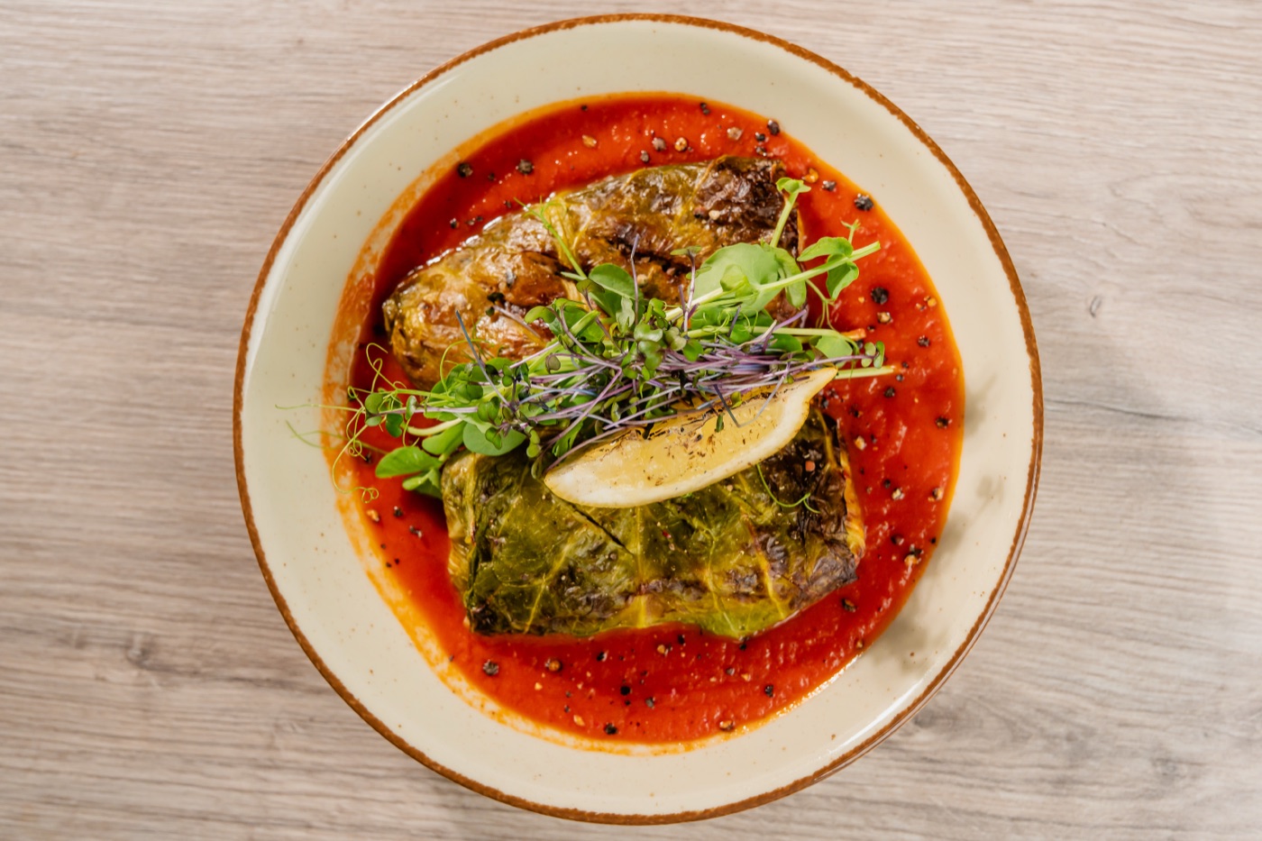 Gołąbki z dorszem i łososiem w aromatycznym sosie pomidorowym, przybrane mikrozieleniną i cytryną