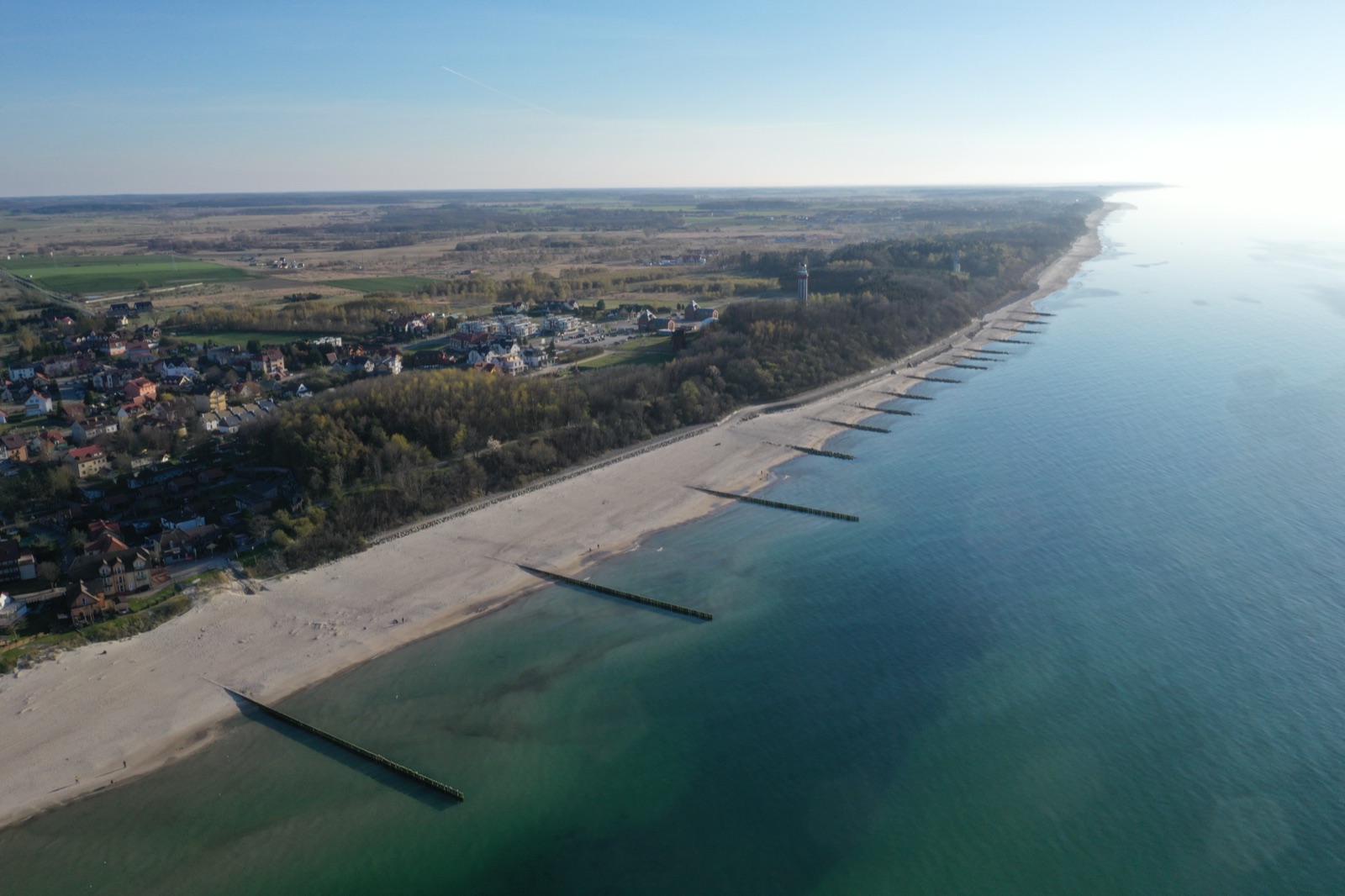 Panorama wybrzeża Niechorza z drona — drewniane falochrony, plaża, domy